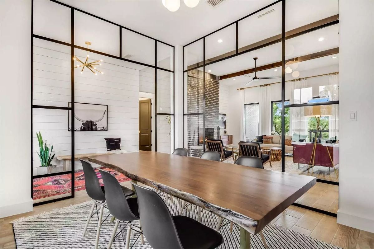 Dining Room Divided by Black-Framed Glass Partitions and Live-Edge Table