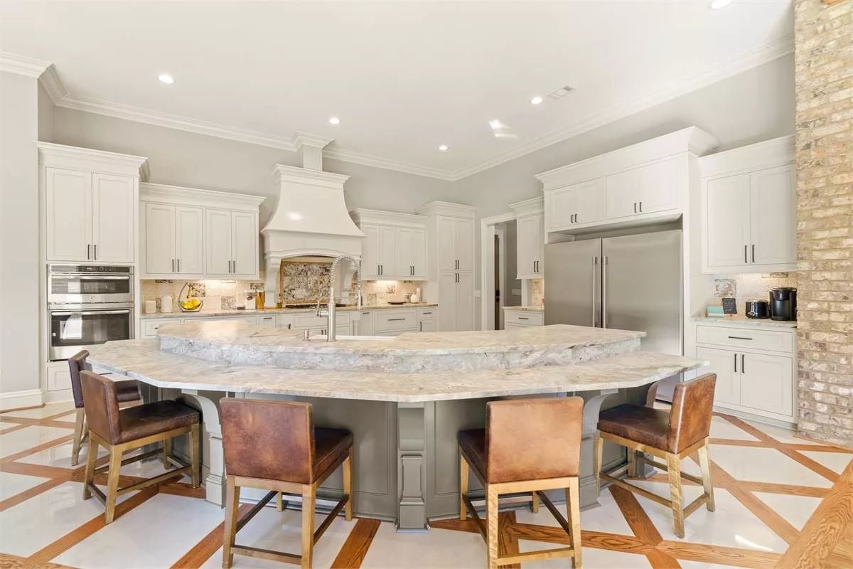 Curved Marble Island with Leather Barstools Commands This Grand Kitchen