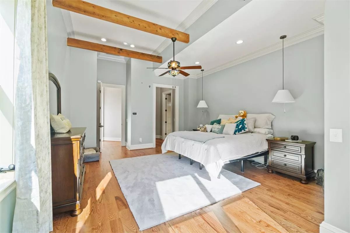 Exposed Beam Ceiling and Hardwood Floors Shape This Spacious Master Bedroom
