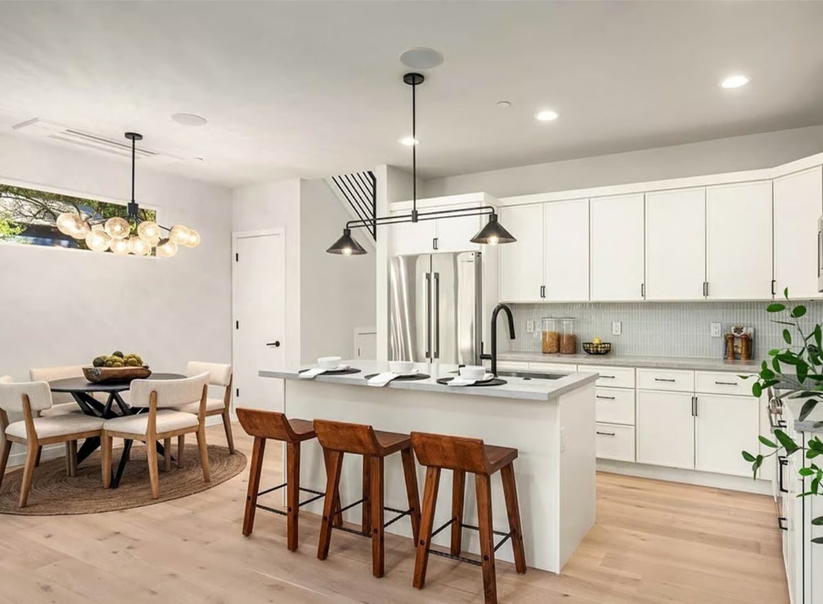 White Cabinets and Warm Wood Stools Define This Open Kitchen and Dining Space