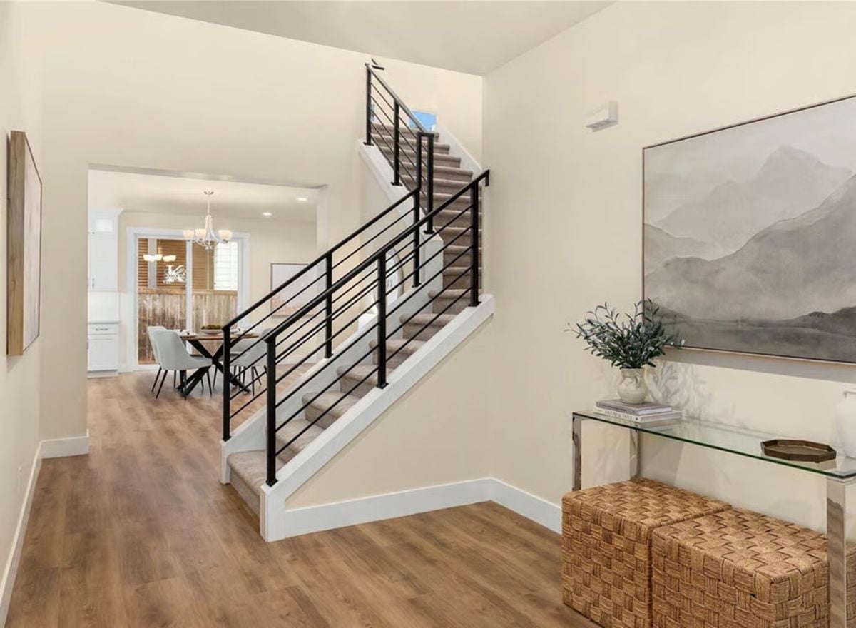 Black Iron Railings and Warm Wood Floors Define This Foyer