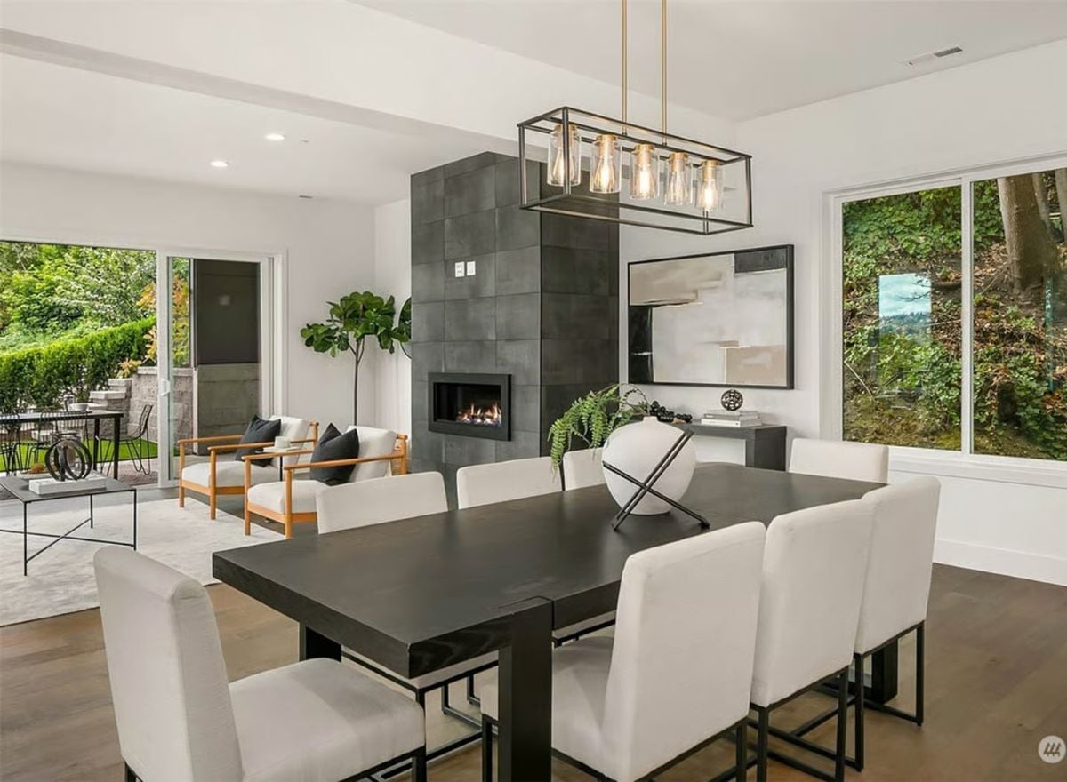 Dark Table, White Chairs, and a Fireplace That Anchors Two Rooms at Once