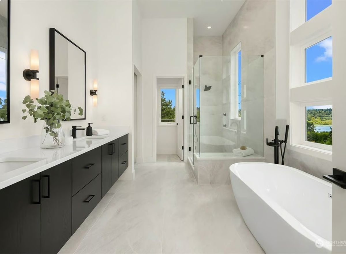 Freestanding Tub, Glass Shower, and Black Hardware Against White Stone