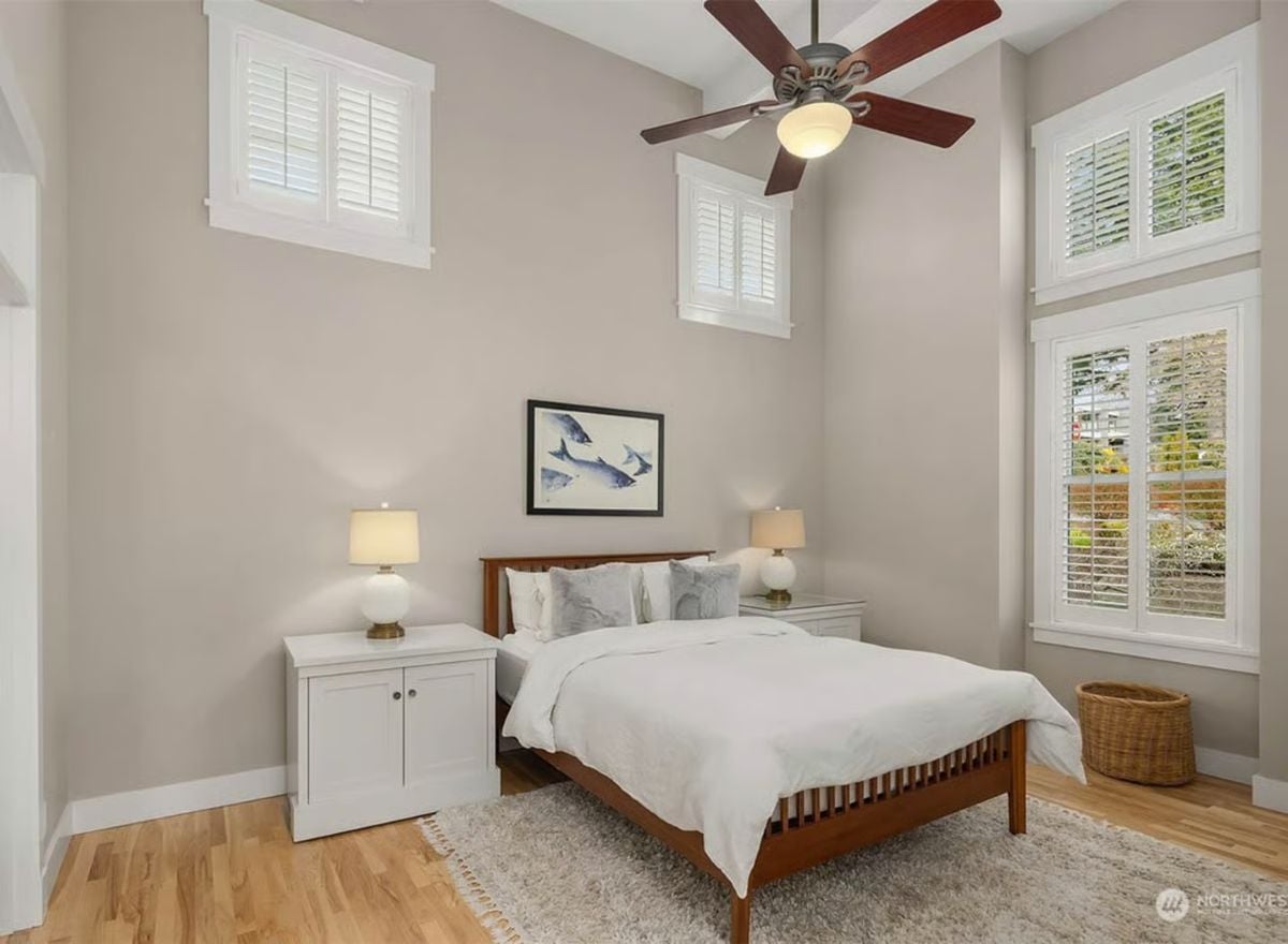 Vaulted Bedroom with Plantation Shutters, Wood Bed Frame, and Fish Art