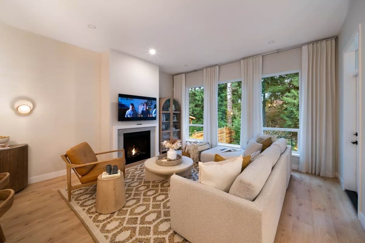 Warm-Toned Living Room Pairs a Stone Fireplace with Forest Views