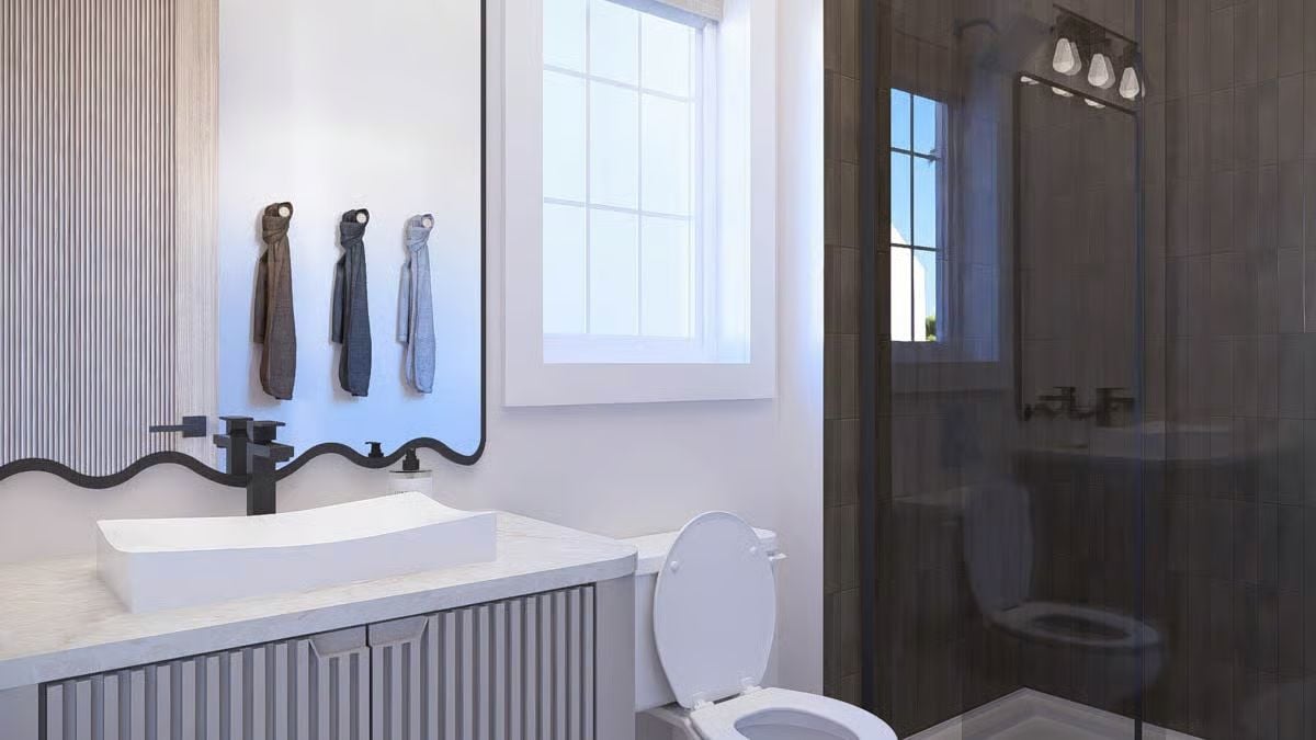 Wavy Mirror Frame and Vessel Sink Bring Soft Curves to a Dark-Tile Bathroom