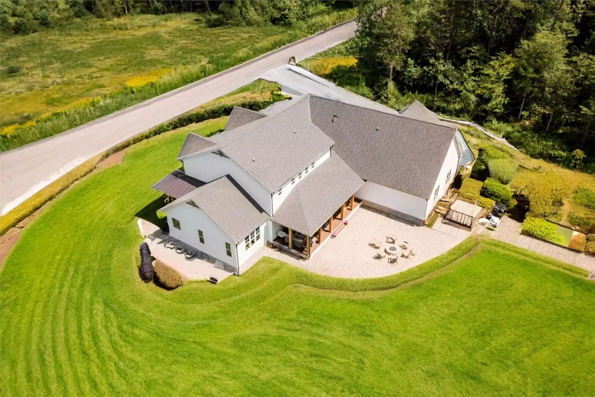 Aerial View of Craftsman Home Surrounded by Manicured Lawn and Wooded Edge