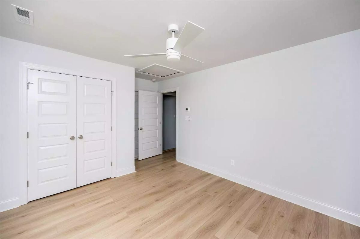 Double French Closet Doors Meet Warm Wood Floors in an Empty Bedroom