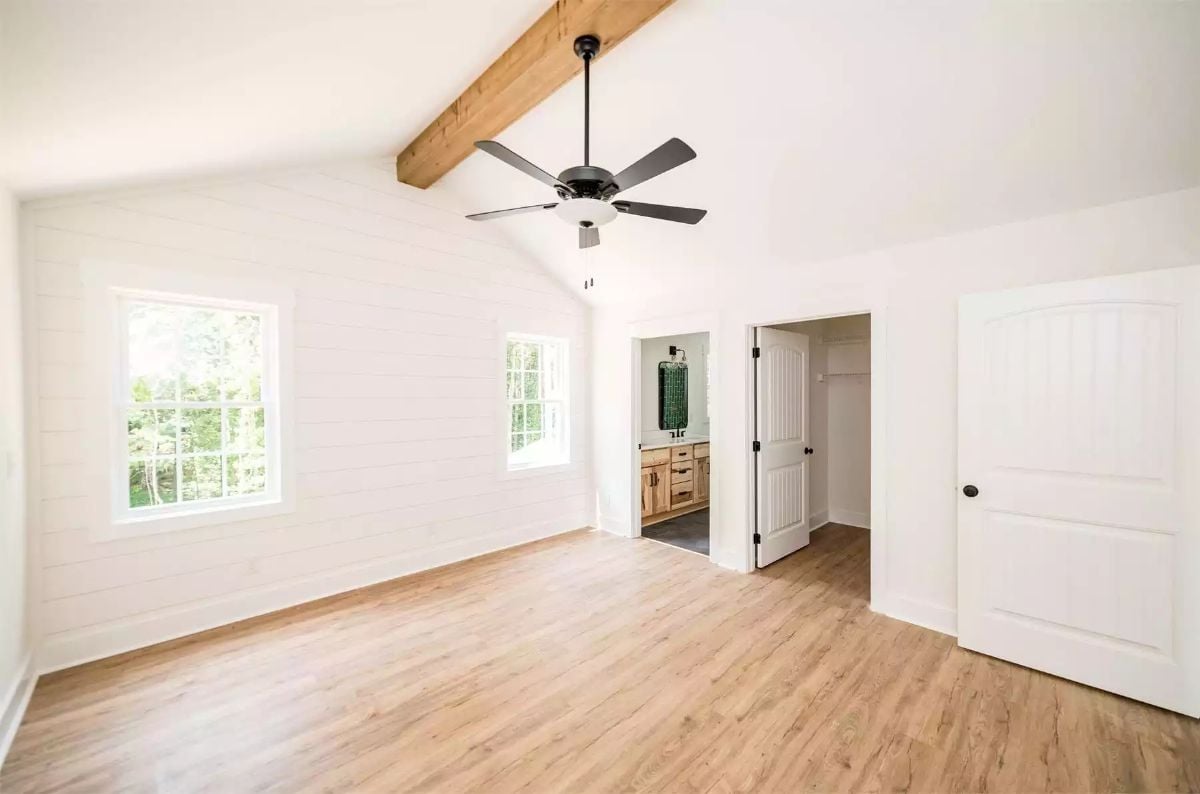 Vaulted Shiplap Walls and Exposed Beam Define a Spacious Primary Bedroom