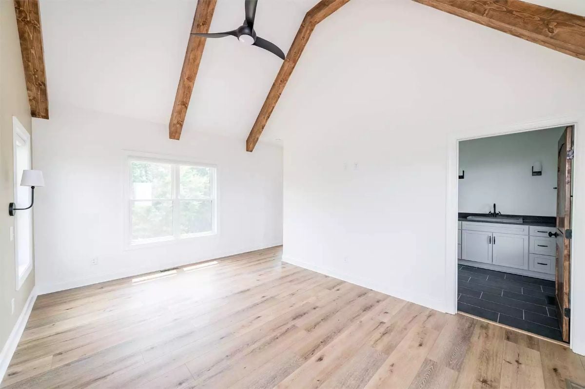 Vaulted Cathedral Ceiling with Exposed Beams Opens This Empty Primary Suite