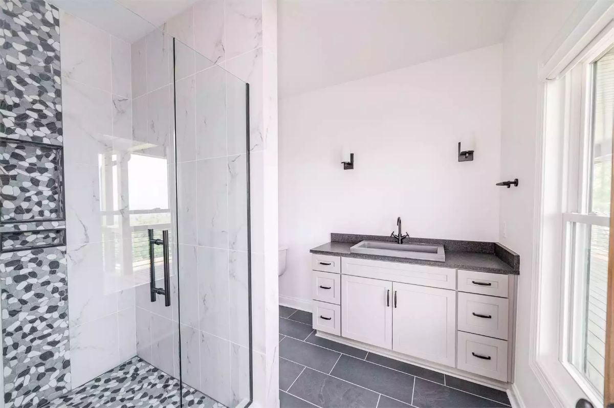 Mosaic Pebble Tile and Marble Surround Share Space in This Walk-In Shower