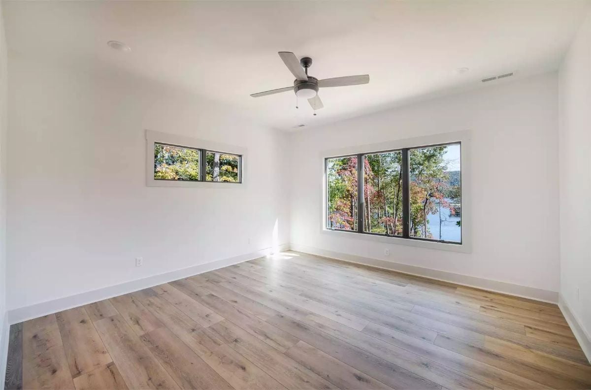 Light Wood Floors and Black-Frame Windows Frame a Treetop Bedroom View