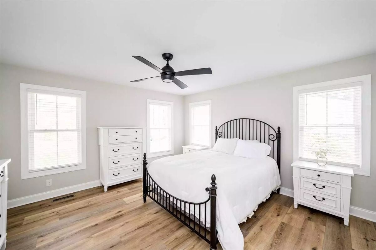 Iron Bed Frame and Black Ceiling Fan Anchor a Farmhouse Bedroom