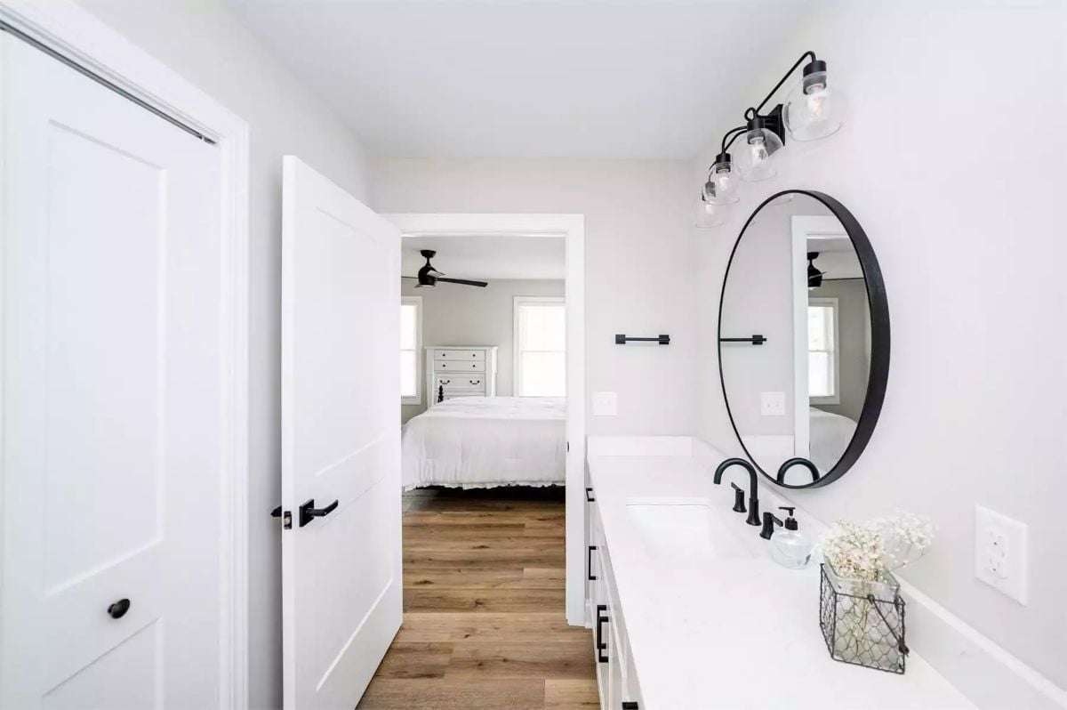 Black Hardware and Round Mirror Bring Farmhouse Character to an Ensuite Bath
