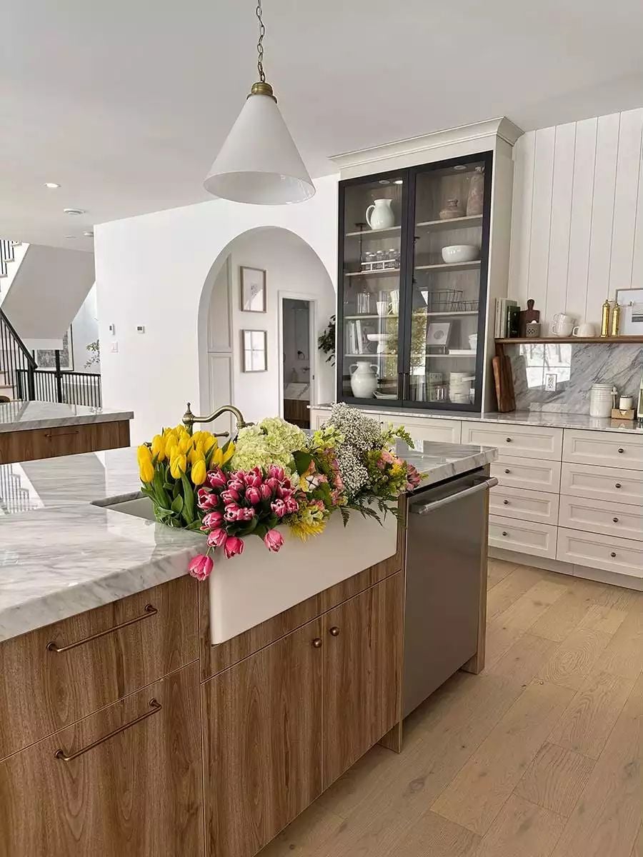 Farmhouse Sink Buried Under Market Flowers on a Wood-Grain Island