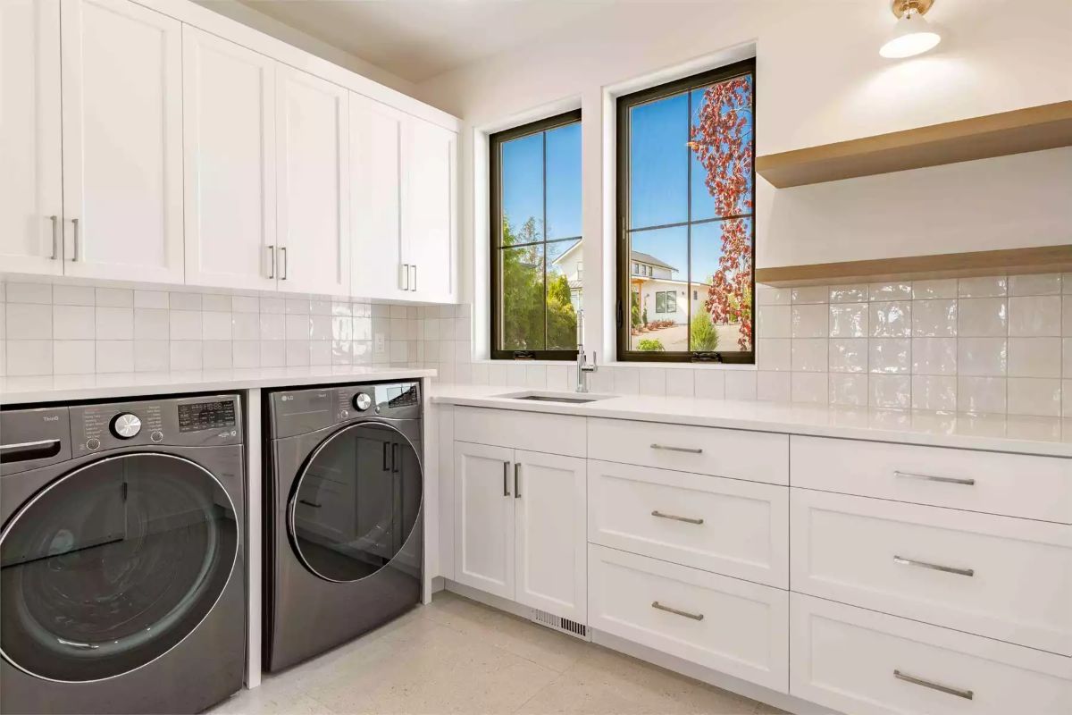 LG Front-Loaders Tucked Under White Shaker Cabinets in a Light-Filled Laundry Room