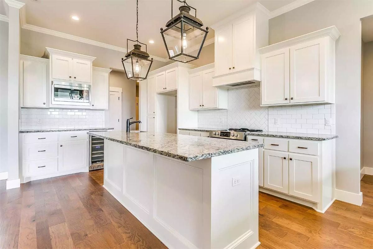 Lantern Pendants and Granite Countertops Ground a Classic White Kitchen