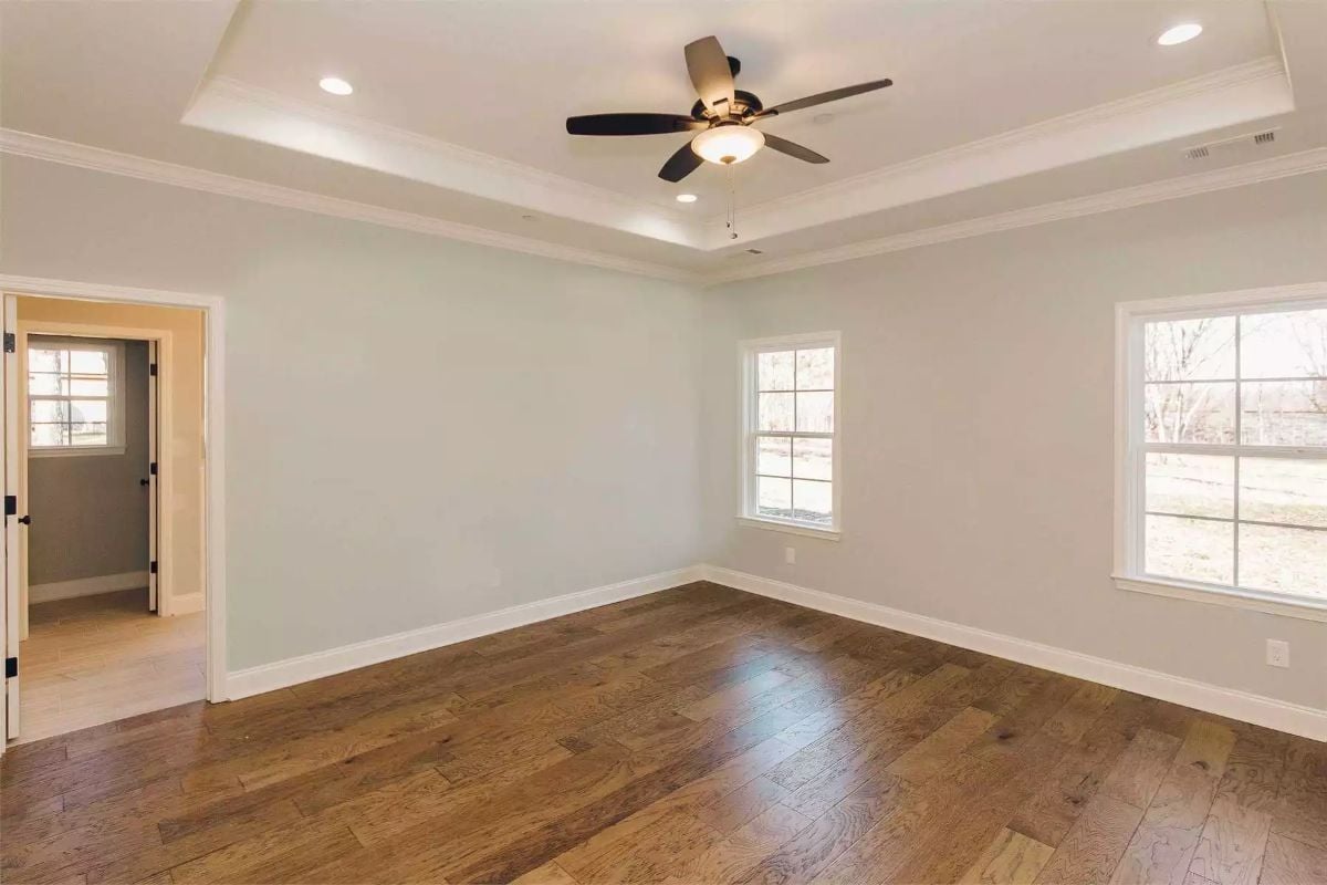 Tray Ceiling and Dark Hardwood Give the Primary Bedroom Some Real Weight