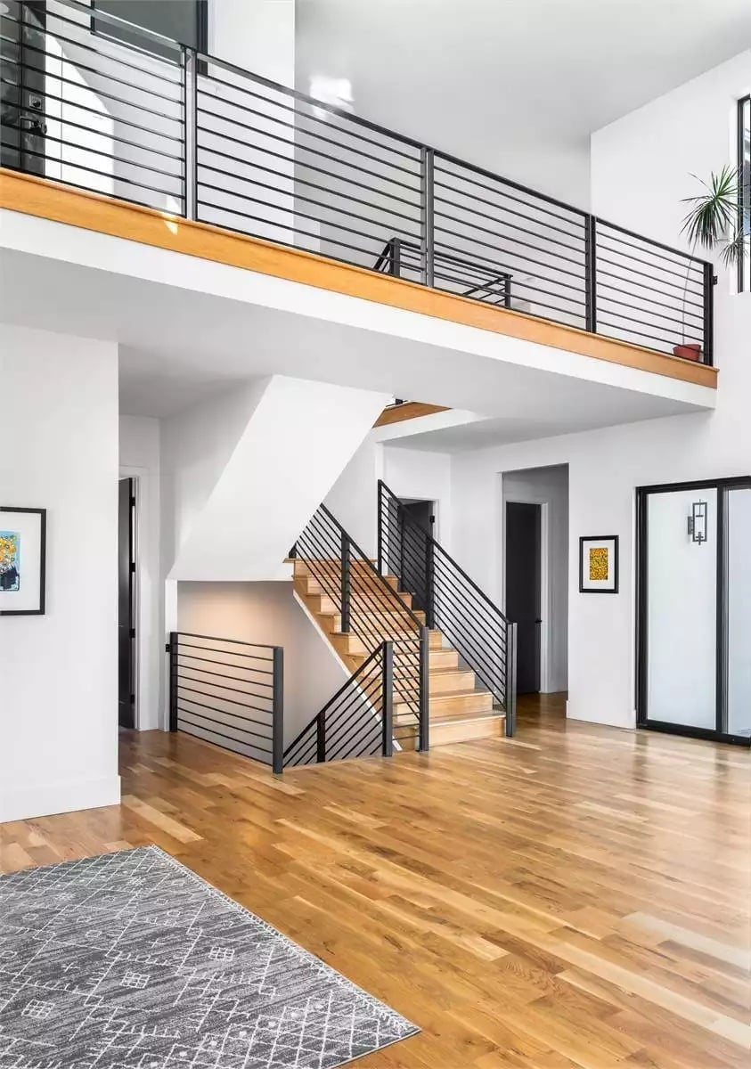 Horizontal Rails, Warm Oak Treads, and a Double-Height Foyer That Actually Earns the Space