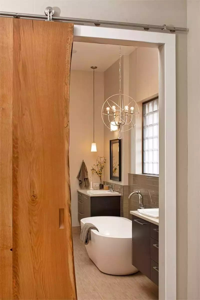 Live-Edge Barn Door Slides Open to Reveal a Freestanding Tub and an Orb Chandelier