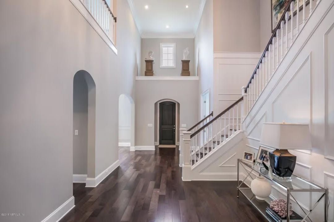 Double-Height Foyer with Wainscoting and a Staircase That Commands Attention
