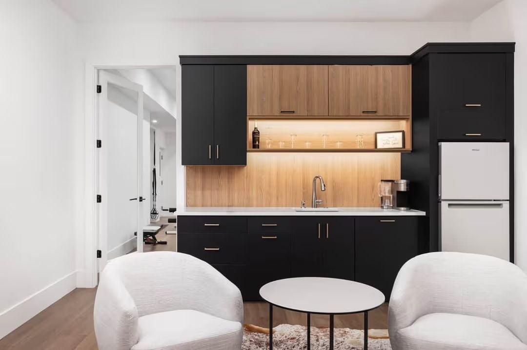 Backlit Shelving and Matte Black Cabinets in a Wet Bar Built for Regular Use