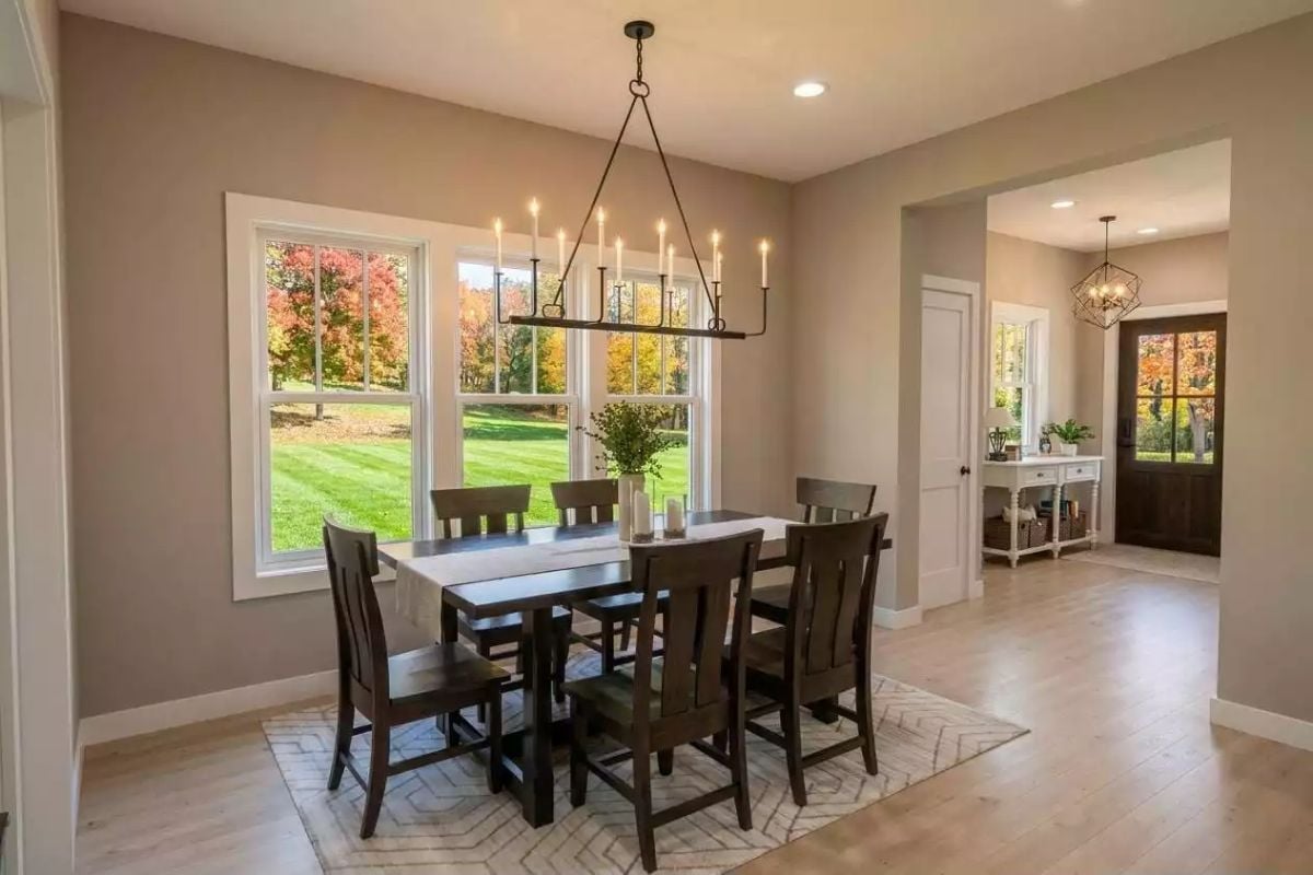 Candle-Style Chandelier Over Dark Wood Dining Set Framed by Fall Color Outside
