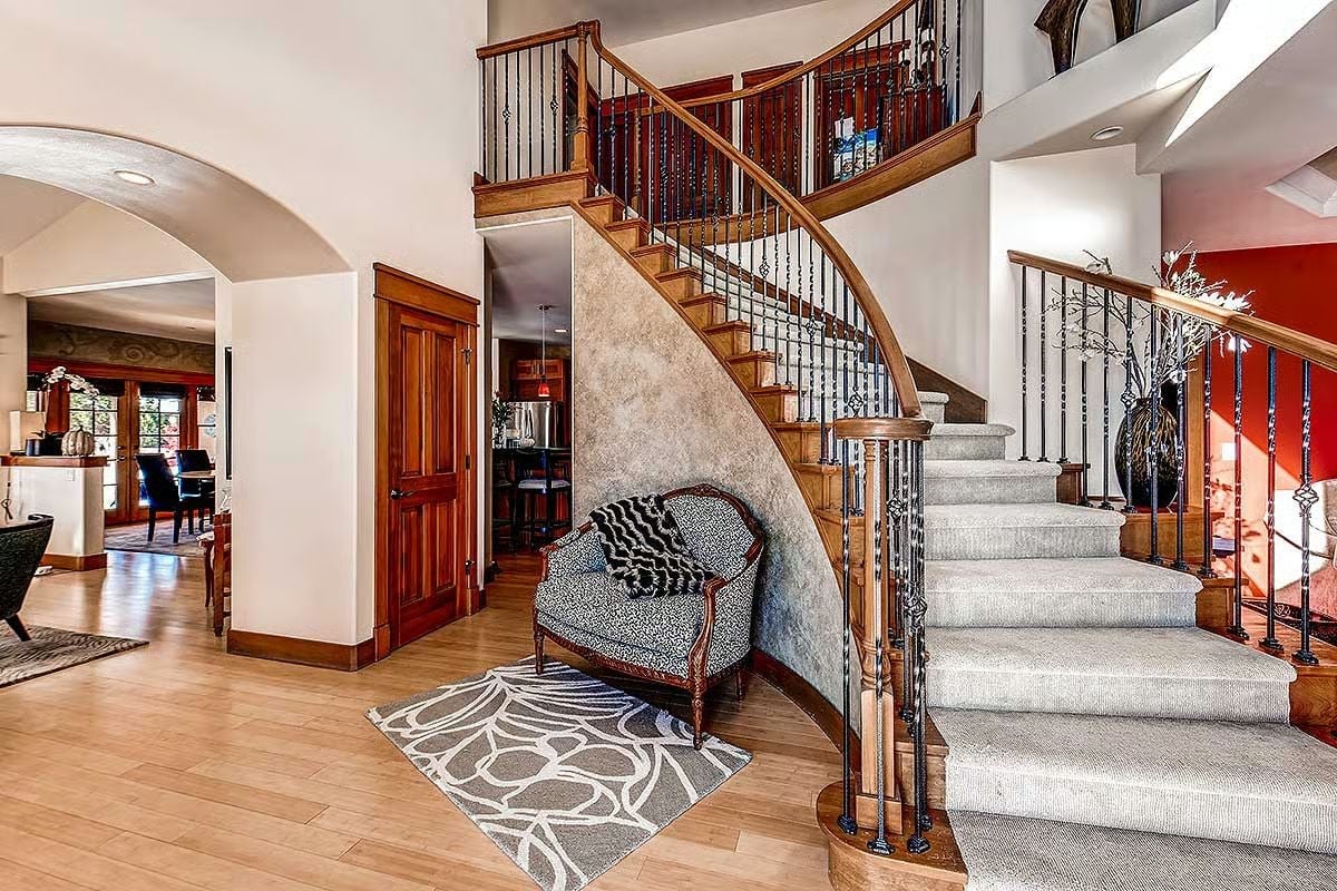 Curved Staircase With Wrought Iron Balusters Sets the Tone at the Front Door