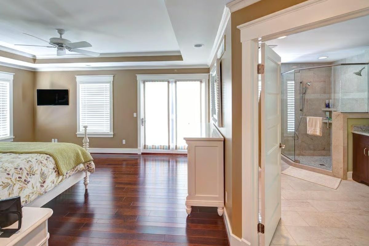 Glass-Enclosed Shower and Hardwood Floors in a Master Suite That Connects Two Spaces