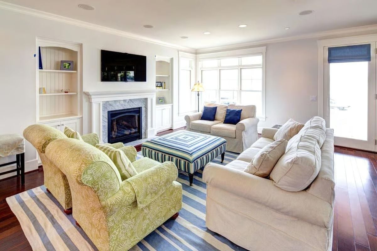 Striped Ottoman, Green Armchairs, and a Marble Fireplace Walk Into a Living Room