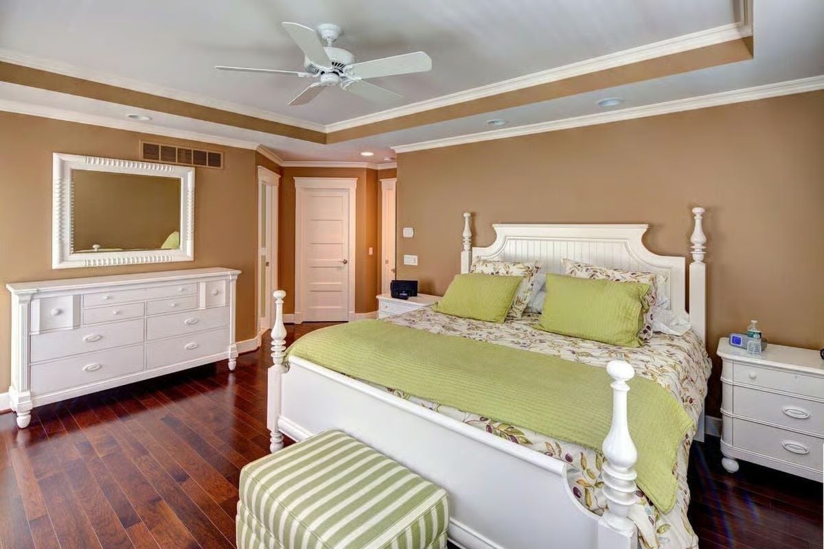 White Poster Bed With Green Accents in a Master Suite Built Around Warm Walls