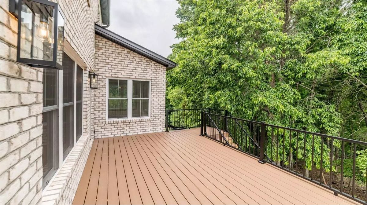 Composite Decking, Black Iron Rails, and a Tree Line That Does the Decorating