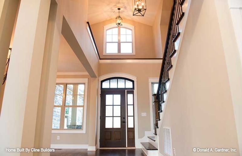 Soaring Foyer With an Arched Door That Sets the Whole Tone
