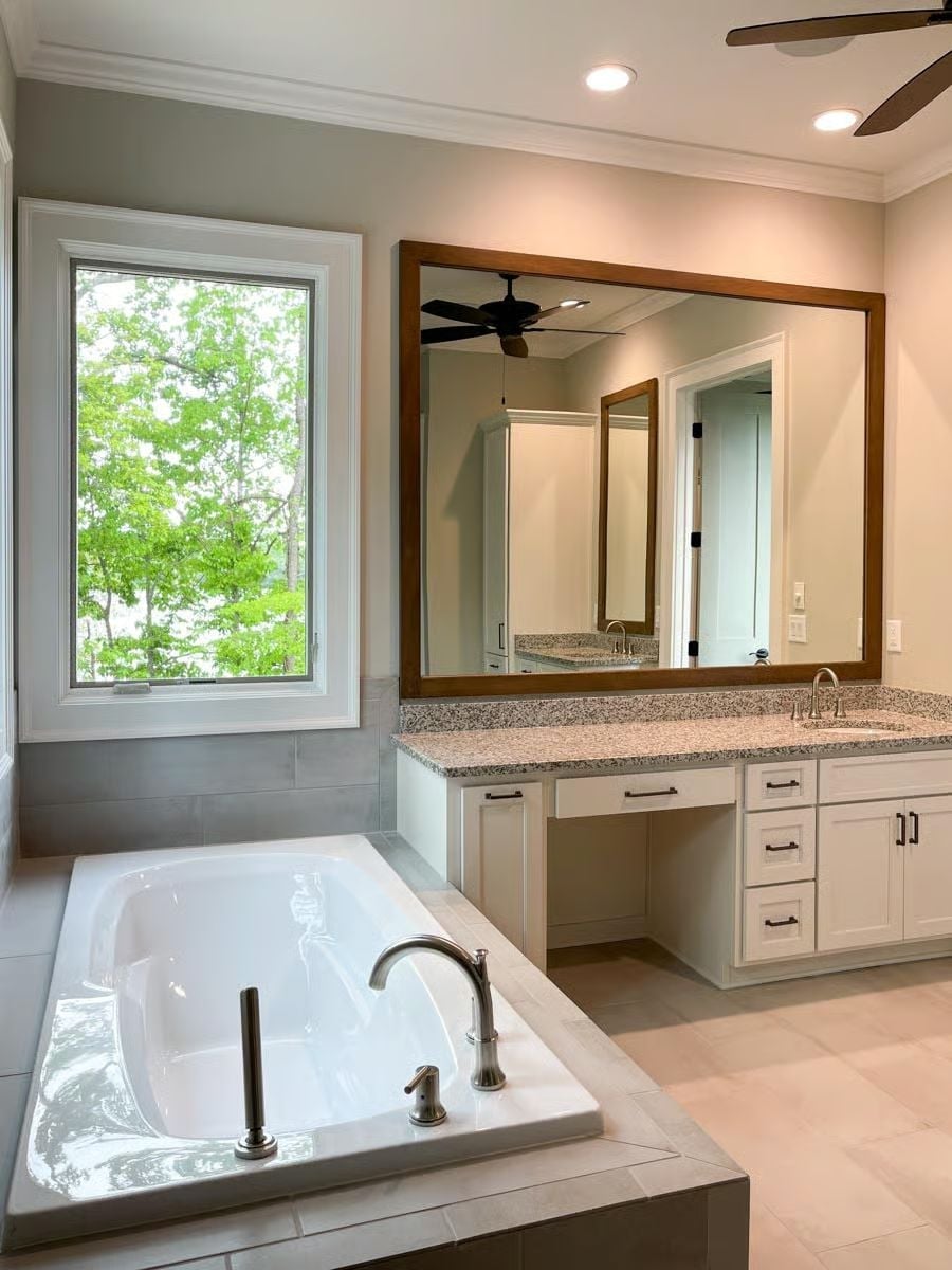 Soaking Tub Framed by a Garden View and a Mirror That Reflects the Whole Room