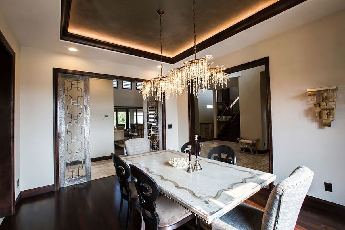 Crystal Chandelier Meets Tray Ceiling With Warm Cove Lighting Above a Marble Dining Table