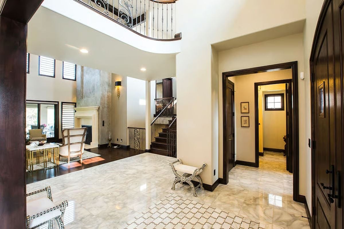 Marble Foyer with Iron Balustrade Above and a Bench That Earns Its Place