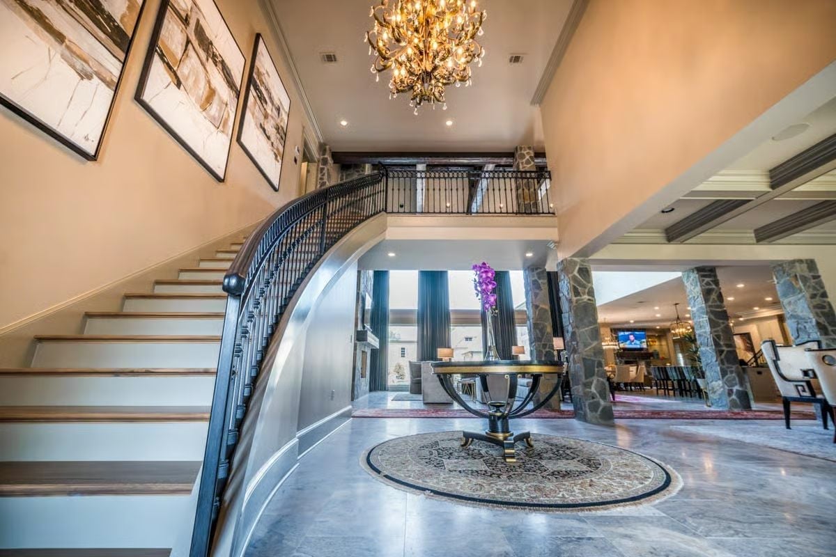 Curved Iron Staircase and a Chandelier That Earns Every Inch of That Ceiling