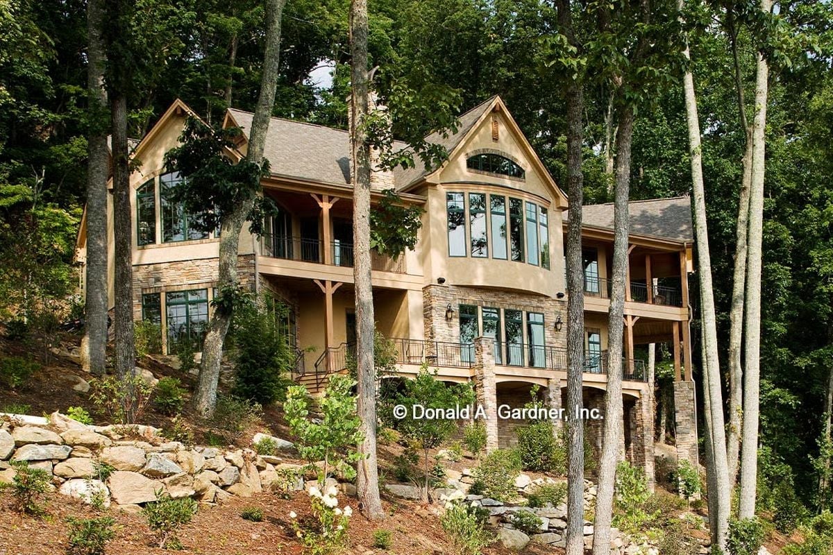 Stucco, Stone, and Tall Glass Pull This Rear Elevation Into the Forest Around It
