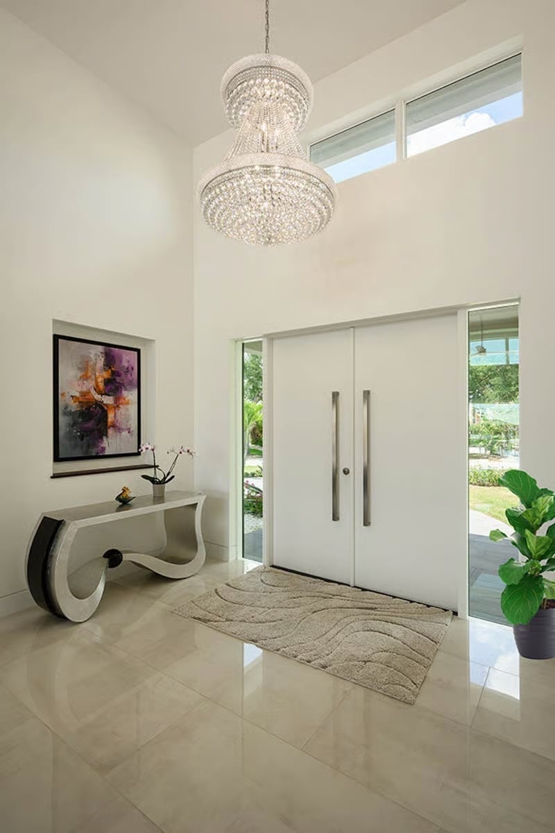 Crystal Chandelier Foyer with Double White Pivot Doors and High Ceilings