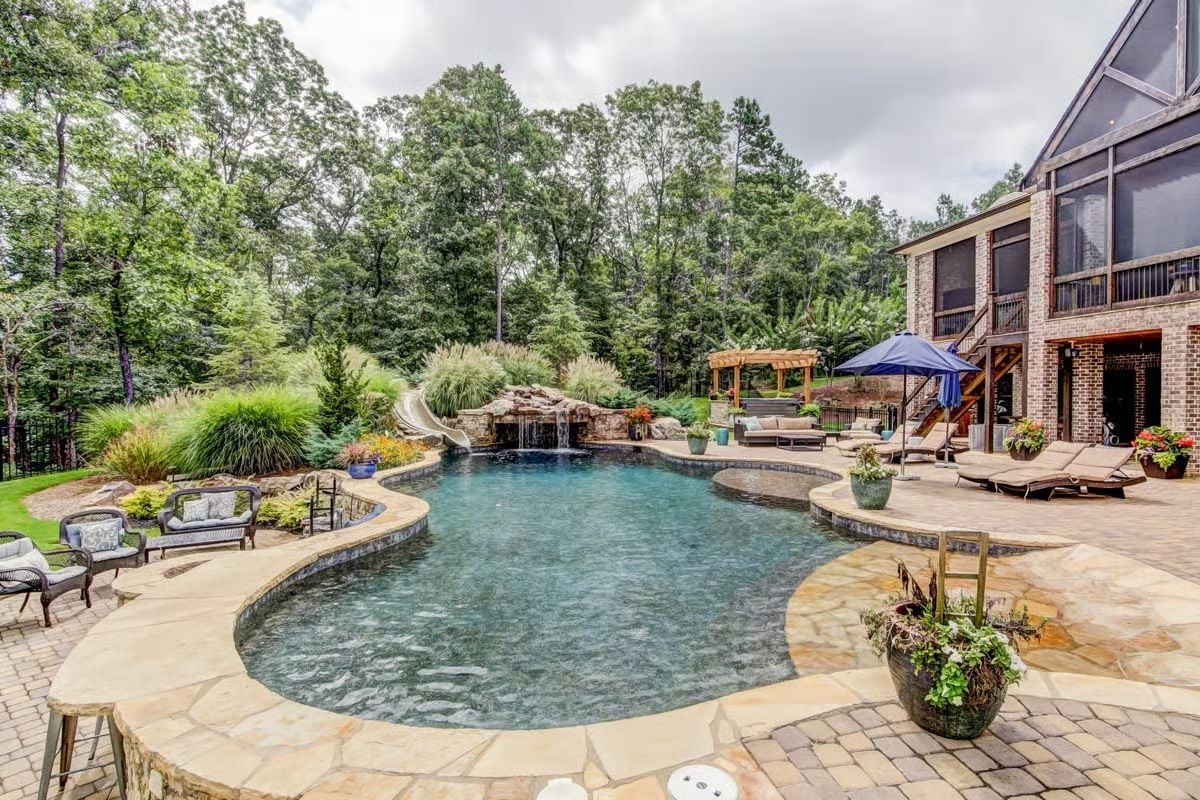 Freeform Pool with Waterfall Slide and Stone Surround Built for Long Summers