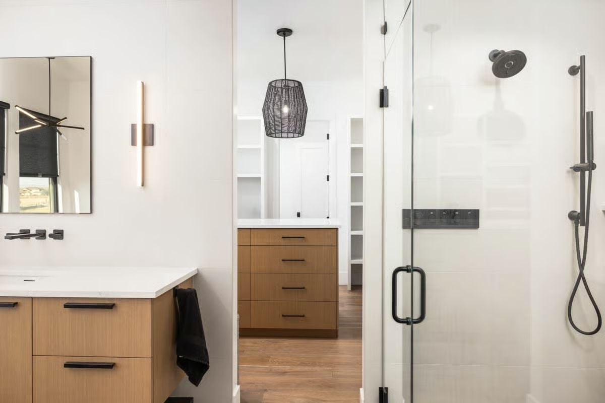 Warm Wood Vanities and Matte Black Hardware Anchor This Primary Bath