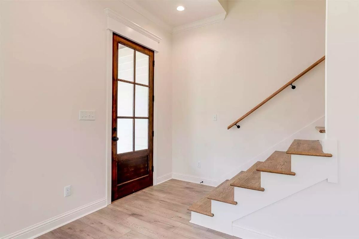 Dark Wood Door With Glass Panes Earns Its Place in a White Entryway