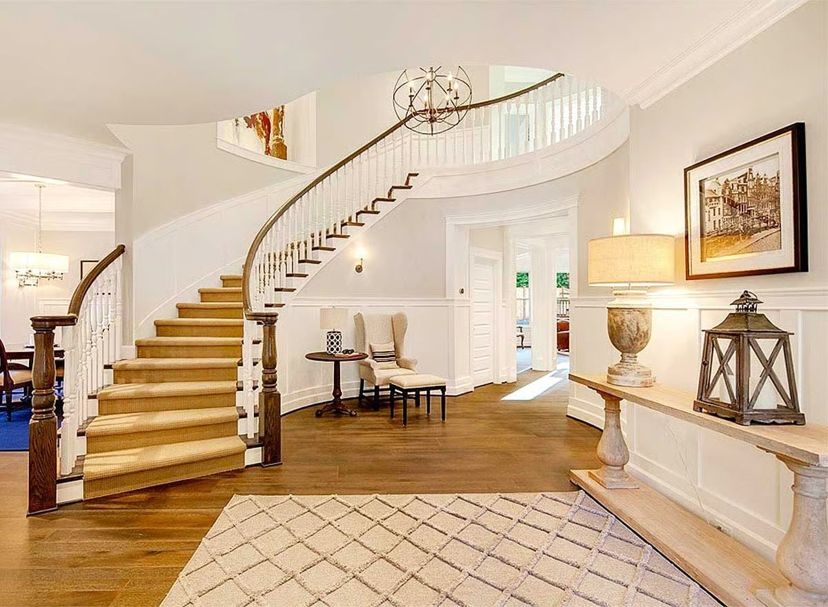 Curved Staircase with Orb Chandelier Anchors a Grand Foyer Worth Coming Home To