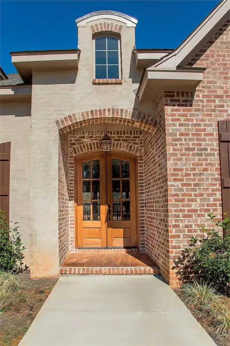 Arched Brick Entry With Double Wood Doors That Sets the Tone Before You're Even Inside