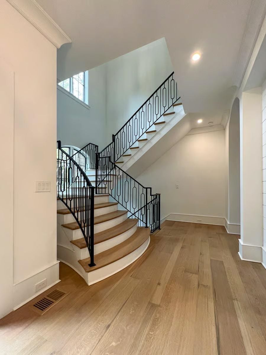 Curved Staircase with Iron Balusters That Earns Every Inch of Foyer Space