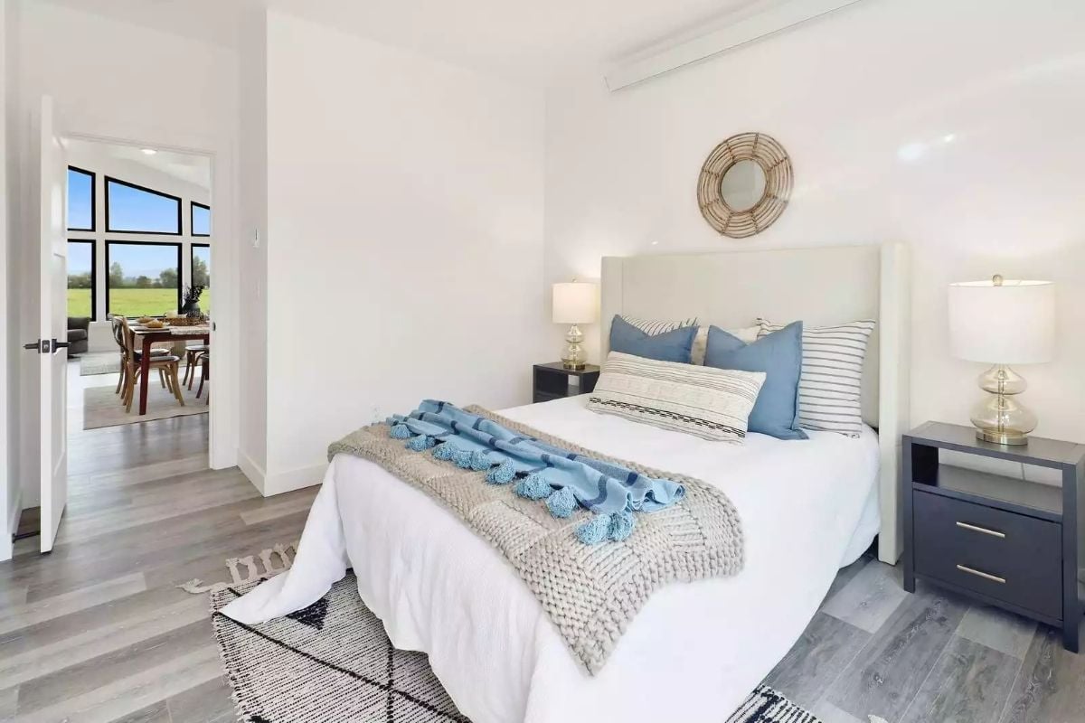 Knitted Throw and Blue Pillows Make a White Bedroom Feel Lived In