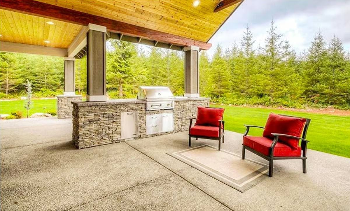 Stone Counters and a Built-In Grill Under a Wood Ceiling Built for Year-Round Outdoor Cooking