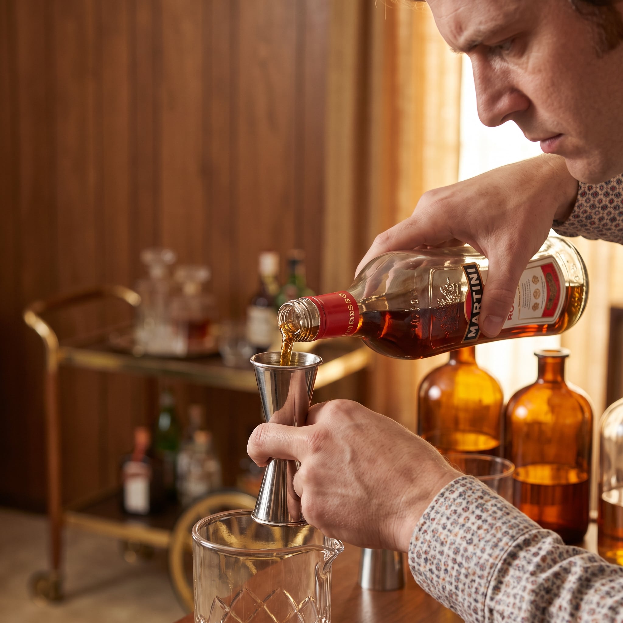 Host preparing cocktails behind a 1970s home bar