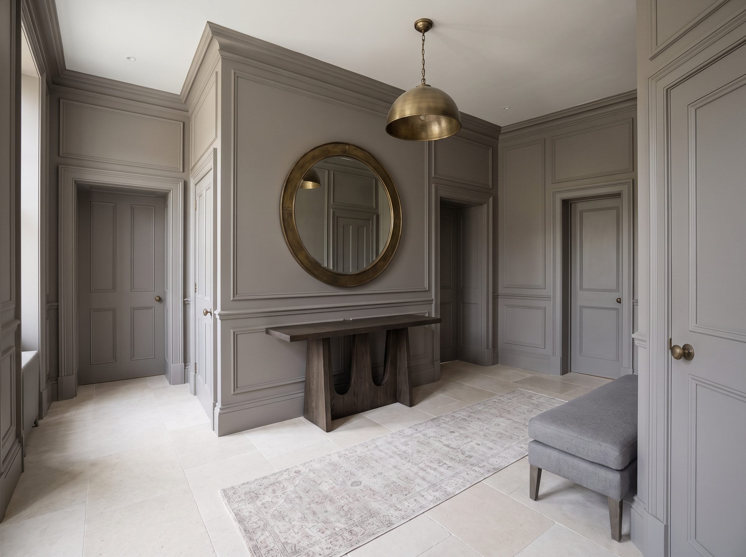 Entry hall with walls, panel molding, and interior doors all painted the same warm-gray, with a dark-oak console and arched
