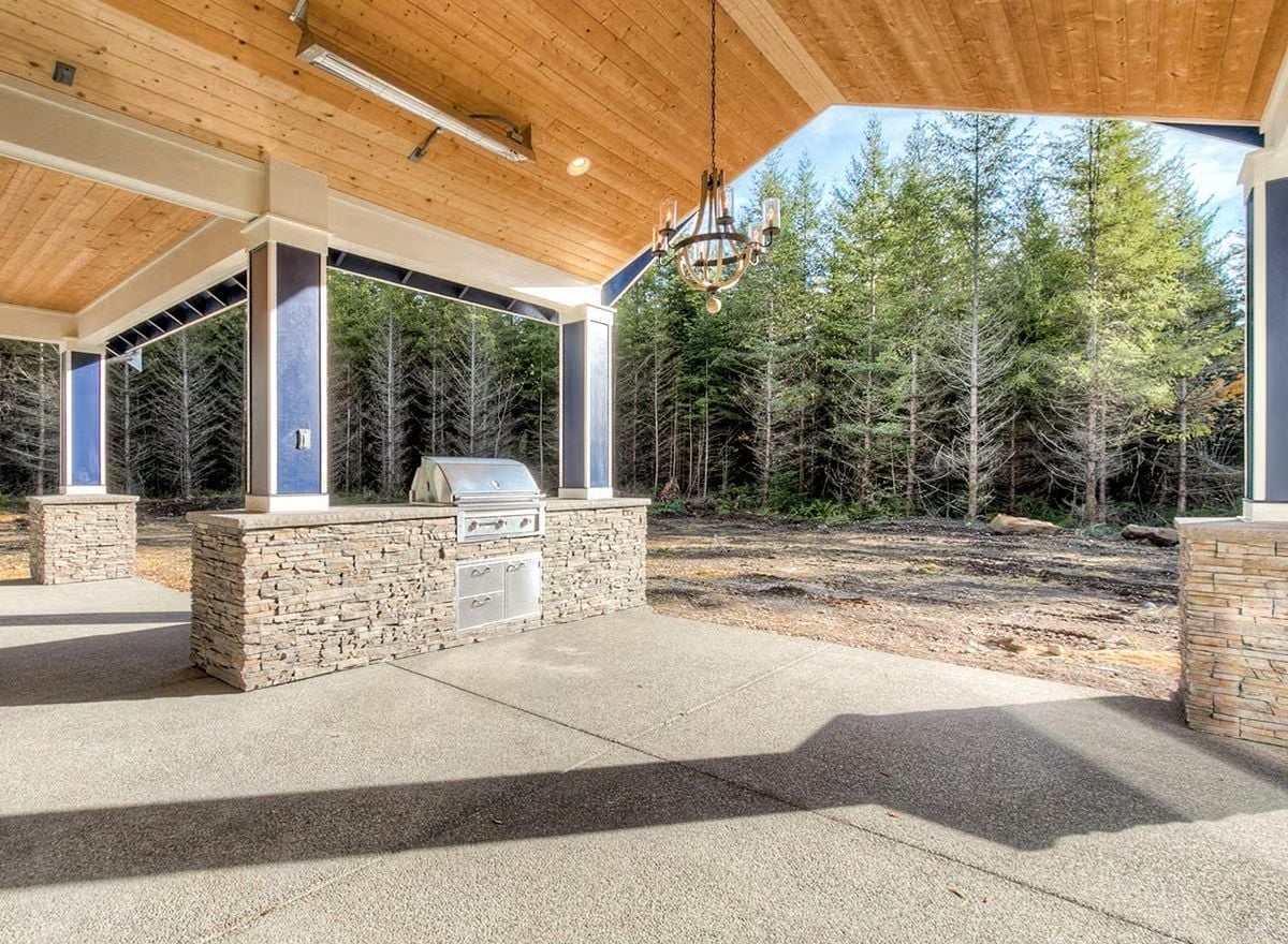 Covered Outdoor Kitchen with Stone Base and a Chandelier That Means Business